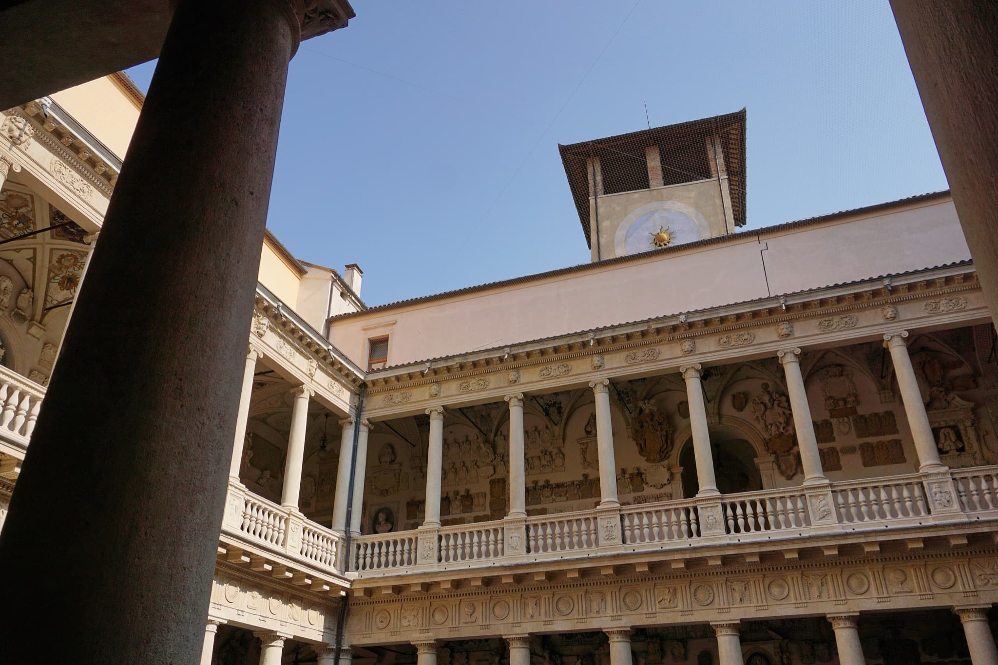 The arcaded Renaissance courtyard of Palazzo del Bo in Padua under a blue sky